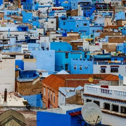 Blue and white houses stacked up a hill in Chefchaouen, with a clear sky
