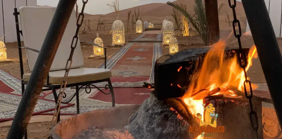 Campfire burning at night with chairs around it and tents in the background, part of an 11 days Marrakech desert tour experience.
