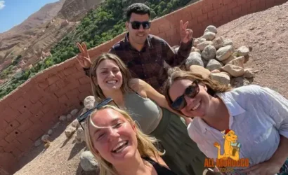 A group of tourists taking a selfie, with joyful expressions and peace signs, during an overnight stay in Dades Valley on a 5-day tour from Marrakech.