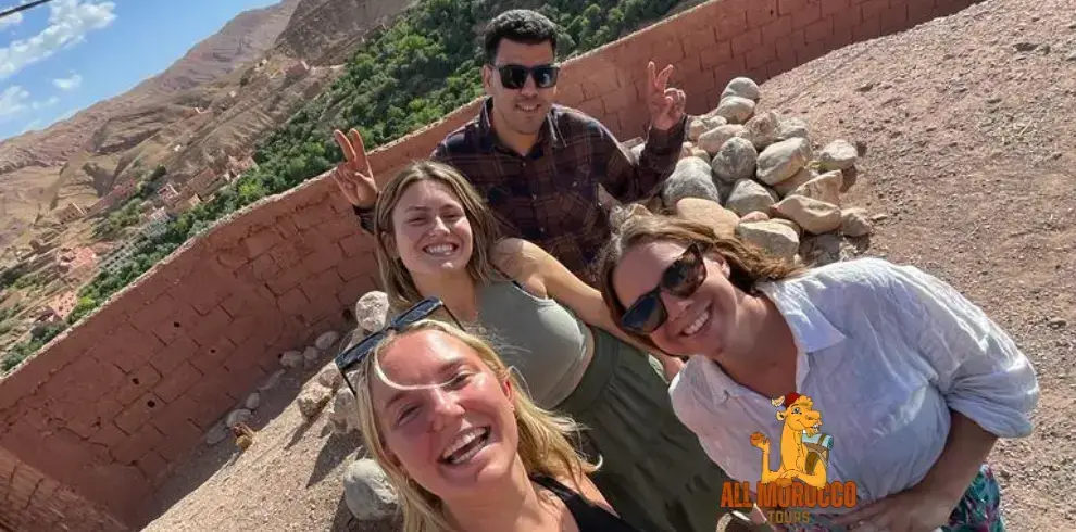 A group of tourists taking a selfie, with joyful expressions and peace signs, during an overnight stay in Dades Valley on a 5-day tour from Marrakech.