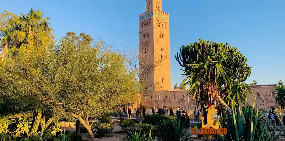 The iconic Koutoubia Mosque stands tall amidst lush palm trees under the clear blue sky a historic and cultural landmark visited on the 5 days desert tour from Fes to Marrakech.