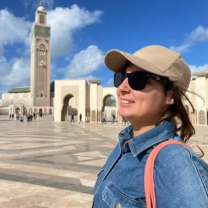 happy visitor in a hat and sunglasses at Hassan II Mosque in Casablanca with blue sky perfect for Casablanca tours category
