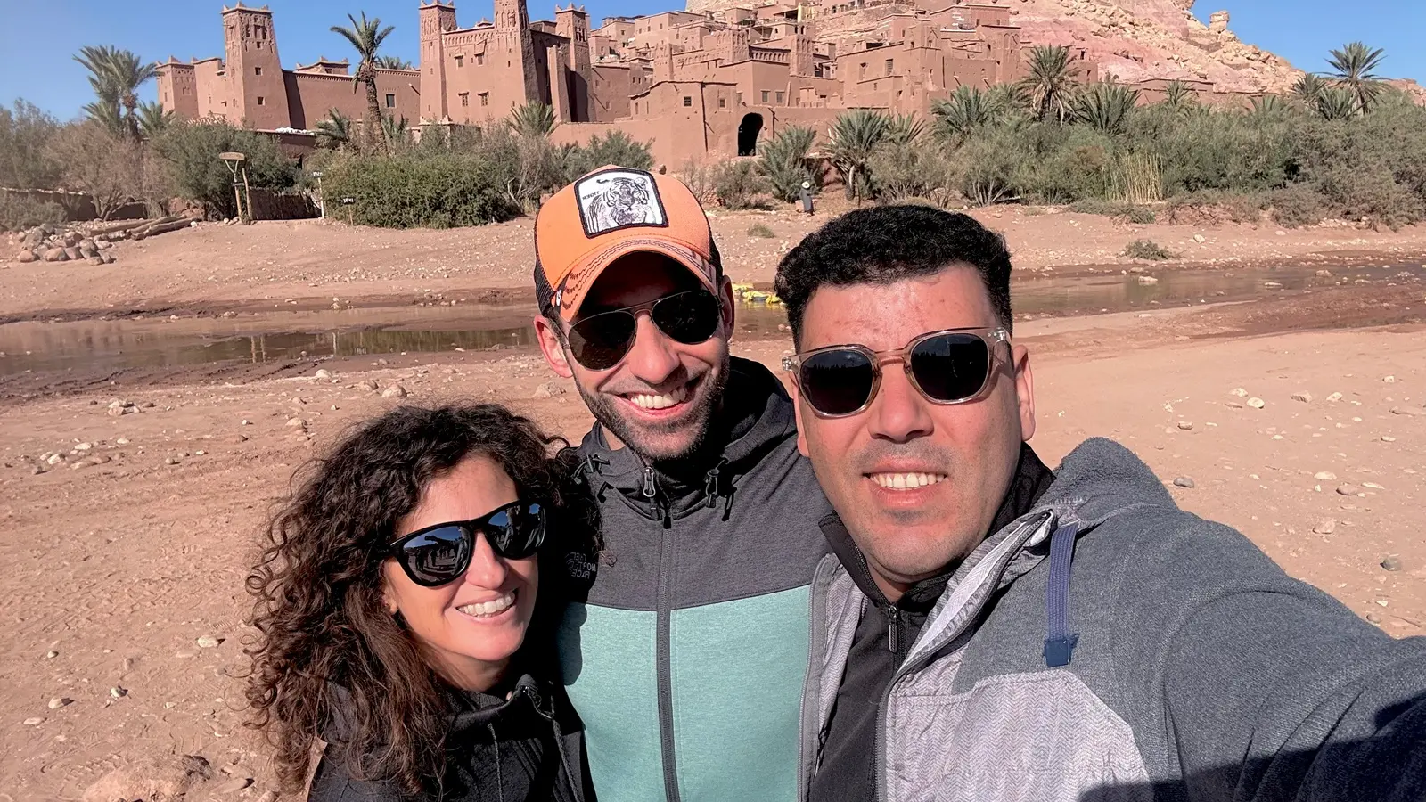 Travelers taking a photo at Kasbah Ait Ben Haddou during a 3 days desert tour from Marrakech to Fes, Morocco