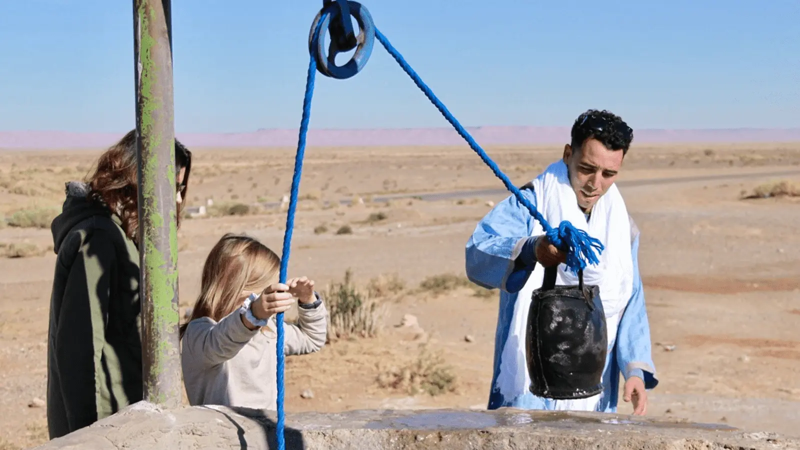 Nomad family in the Moroccan desert using natural well water for daily life